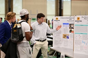 A student presents research to two classmates at the I.S. Symposium