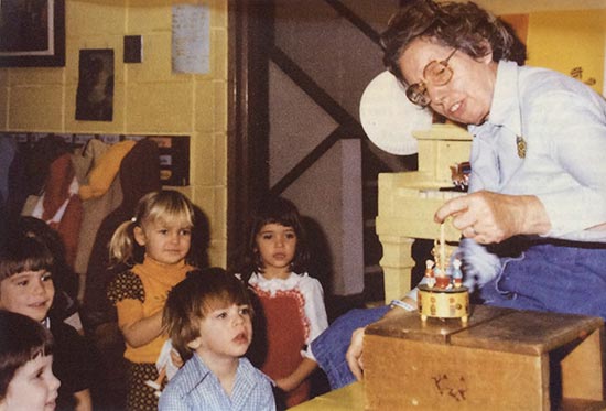 Historical photo of teacher showing students a special music box