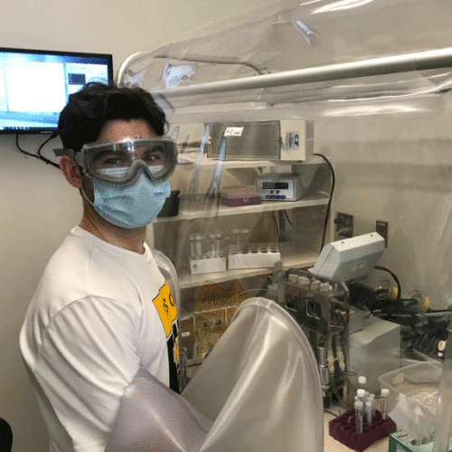 Wooster student Jack Redick wearing eye protection and a face mask working in a lab