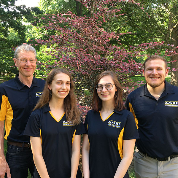 group of four people pose for photo in black polo shirts at The College of Wooster