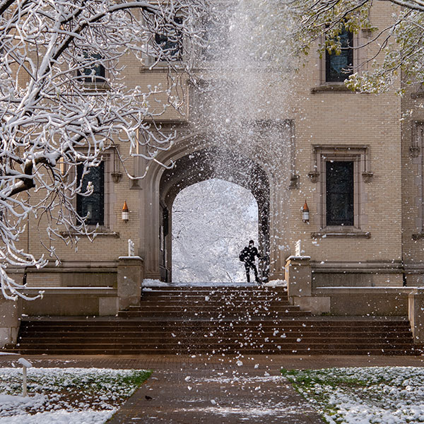 snow falls from the trees in front of Kauke Hall at The College of Wooster