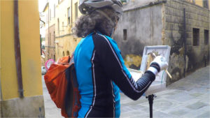 Photo of artist painting in city alley wearing recreational gear