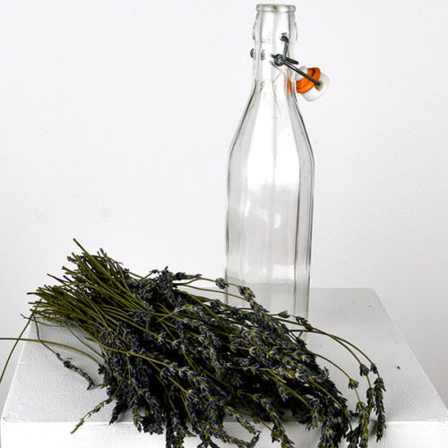 Tall glass bottle pictured with sprigs of lavender