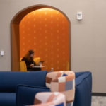 A student doing schoolwork in a yellow theme lounge on the second floor of Lowry Center at The College of Wooster.