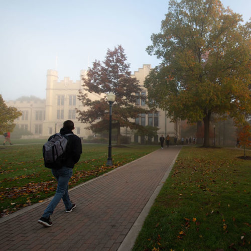 A student walks in the fog in front of Kauke Hall at The College of Wooster.