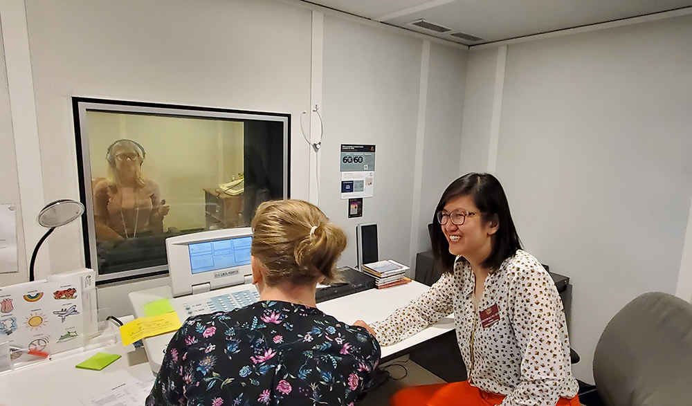 Stacey Lim sits in front of an audiometer to watch as one of her students tests another student's hearing.